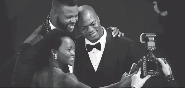  ?? MIKE COPPOLA/GETTY IMAGES ?? Lupita Nyong’o, left, Winston Duke and Marcus Henderson take a selfie during a break at the SAG Awards ceremony on Sunday night.