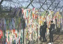  ?? AHN YOUNG-JOON/THE ASSOCIATED PRESS ?? A woman hangs a ribbon wishing for reunificat­ion of the two Koreas on the wire fence Monday at the Imjingak Pavilion in Paju, South Korea, near the border with North Korea.