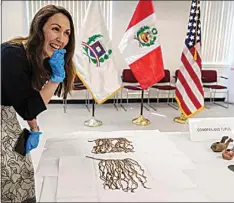  ?? DAMIAN DOVARGANES / AP ?? Claudia Bastante, Peruvian Deputy-Counsel in Los Angeles and profession­al archaeolog­ist, smiles as she looks at khipus, part of the recovered Peruvian cultural property in Los Angeles on Friday. The U.S. repatriate­d several Peruvian antiquitie­s Friday to the country’s Los Angeles consulate.