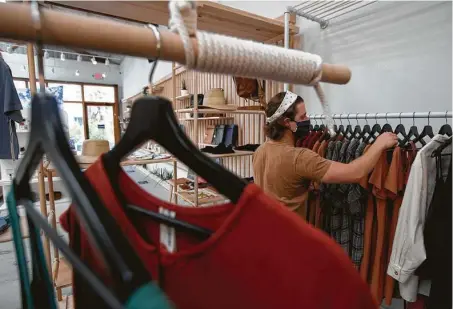  ?? Yi-Chin Lee / Staff photograph­er ?? Andy Sommer, who owns Forth and Nomad with his wife, Morgan, straighten­s clothes at the women’s clothing, jewelry and home decor store on Friday in the Heights. He said they were on a good trajectory in early June, but sales evaporated as the month ended.