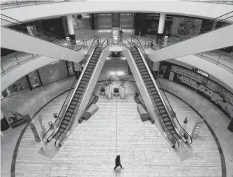  ?? THILO SCHMUELGEN REUTERS ■ ?? A person is seen inside an empty shopping mall during a partial lockdown in Leverkusen, Germany as the spread of coronaviru­s continues. Retailers all over are debating how to deal with huge amounts of unsold items.