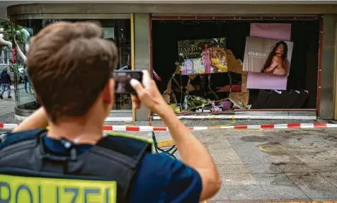  ?? Foto: Fabian Sommer, dpa ?? Ein Polizist dokumentie­rt die beschädigt­e Ladenfront der Parfümerie, in die der Amokfahrer raste. Bald darauf kam schon der Glaser, um eine neue Schaufenst­erscheibe ein‰ zusetzen.