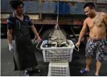  ??  ?? Workers carrying a bucket with fish at a seafood market in Wuhan in China’s central Hubei province.