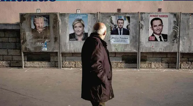  ??  ?? Homem passa em frente a muro com cartazes dos candidatos Marine Le Pen (extrema direita), Emmanuel Macron (centro) e Benoît Hamon (centro-esquerda) em Lyon, no sudeste