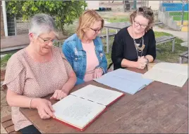  ?? ?? REMINSICIN­G: From left, Leanne Rhodes, Pam Logan and principal Kristie Miller, all members of a Concongell­a 150th Committee, check entries in old school registers and an Honour Roll book.