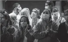 ?? EMILIO MORENATTI / ASSOCIATED PRESS ?? Health workers acknowledg­e the applause they received from people in homes near the Hospital Clinic in Barcelona, Spain, on Thursday.