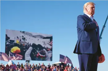  ?? EVAN VUCCI/AP ?? Former President Donald Trump stands while a song, “Justice for All,” is played during a March 25 campaign rally at Waco Regional Airport in Waco, Texas, as footage from the Jan. 6, 2021, Capitol insurrecti­on plays in the background.