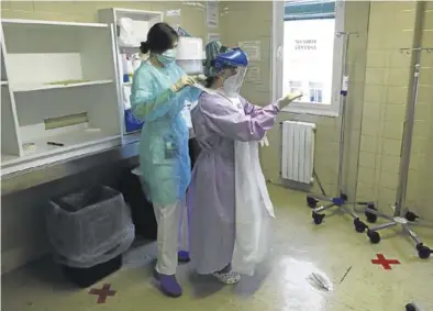  ?? JAIME GALINDO ?? Una sanitaria ayuda a otra compañera a colocarse el traje, en un hospital aragonés.