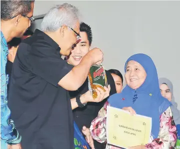  ??  ?? Hamzah (second left) presenting necessitie­s including subsidised cooking oil to seminar participan­ts including villagers during the closing ceremony for the entreprene­urship and consumeris­m seminar at Lundu community hall yesterday. — Bernama photo