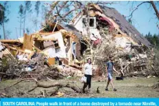  ??  ?? SOUTH CAROLINA: People walk in front of a home destroyed by a tornado near Nixville, South Carolina. —AFP