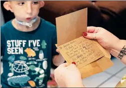  ?? ?? Cherrie Hamilton opens a Christmas card Dec. 30 as her son, Levi “Cheeky” Hamilton, looks on in Fort Myers, Fla.