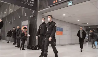  ?? -AFP ?? Policemen wearing protection masks patrol the arrival Terminal of Charles De Gaulle Airport in France. The virus has spread outside Asia and also harmed financial markets.