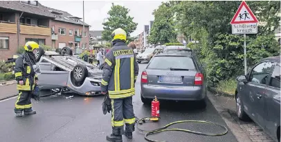  ?? FOTOS (2): DANIEL BOTHE ?? Die Feuerwehr rückte zum Unfallort an die Albertus-Magnus-Straße aus. Ein Auto landete durch die Wucht auf dem Dach. Die Fahrerin wurde laut Polizei leicht verletzt.