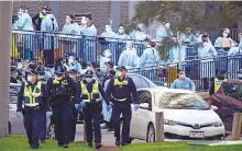  ?? AP ?? Police officers and health care workers are stationed outside a public housing tower that is locked down as a coronaviru­s hotspot in Melbourne yesterday.