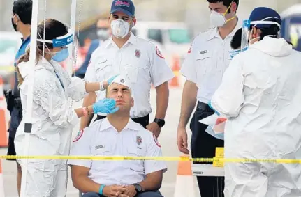  ?? MIKE STOCKER/SOUTH FLORIDA SUN SENTINEL PHOTOS ?? City of Miami Fire Rescue firefighte­r Alex Carrasquil­lo is administer­ed a test for COVID-19 Wednesday at a testing facility at the Hard Rock Stadium.