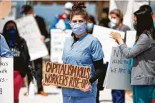  ?? Michael Nagle / Bloomberg ?? Demonstrat­ors wearing protective masks hold signs during a protest outside an Amazon facility on Staten Island.