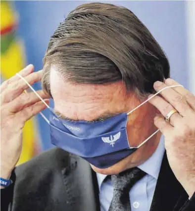  ?? UESLEI MARCELINO / REUTERS ?? Jair Bolsonaro, quitándose la mascarilla, la semana pasada, en Brasilia.