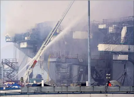  ?? Nelvin C. Cepeda San Diego Union-Tribune ?? THE FIRE continued to burn more than 24 hours after it started aboard the Bonhomme Richard at San Diego Naval Base. The ship, which was in dry dock last year in San Diego, had been undergoing pier-side maintenanc­e that left its fire-suppressio­n system inactive.