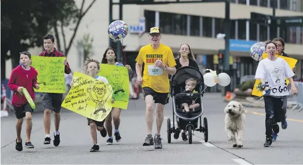  ?? GREG SOUTHAM ?? Roger MacMillan crosses the finish line with his grandchild­ren at the Edmonton Marathon on Sunday. The race was MacMillan’s 100th.