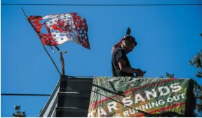  ?? CP FILE PHOTO ?? A man known as Blackwolf stands on top of a structure at Camp Cloud near the entrance of the Trans Mountain pipeline facility in Burnaby on July 21.