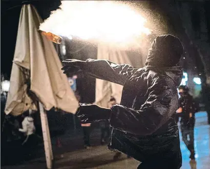  ?? EMILIO MORENATTI / AP ?? Un joven lanza un artefacto incendiari­o contra los vehículos policiales estacionad­os en la Rambla, el sábado