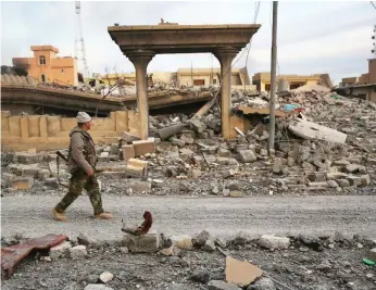  ??  ?? A peshmerga soldier walks past the rubble of a neighbourh­ood in Sinjar days after recapturin­g the town from ISIL. As the focus shifts to rebuilding, Iraq will struggle to meet the cost of peace