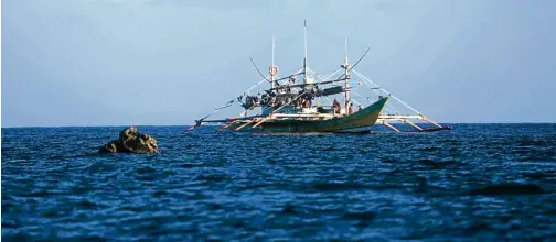  ??  ?? A “mother boat” of Filipino fishermen is anchored near the shoal.