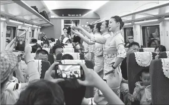  ?? WANG JINGYI / XINHUA ?? Staff members perform a dance on the inaugural train from Xishuangba­nna, Yunnan province, to Luang Prabang, Laos, on Saturday.