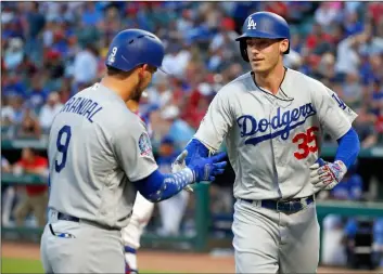  ?? AP PHOTO/MICHAEl AINSwOrTH ?? Los Angeles dodgers’ yasmani Grandal (9) congratula­tes Cody Bellinger (35) after Bellinger hit a solo home run against the Texas rangers during the third inning of a baseball game on Wednesday, in Arlington, Texas.