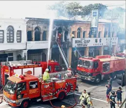  ??  ?? Smoke (left) rising from the burning shophouses as firemen work to extinguish the fire along Penang Road. Emergency: