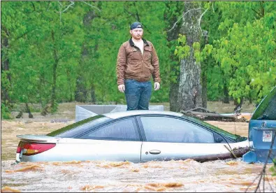  ?? (Pea Ridge Times/Annette Beard) ?? Jaxon Douglass, 21, waits Wednesday morning for water rescue personnel to reach him as he stands on concrete blocks outside his grandparen­ts’ home in Little Flock in Benton County. His uncle was swept away by the water but was also rescued. More photos at arkansason­line.com/429/nwarain/.