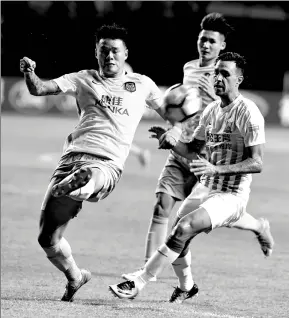  ?? LU HANXIN / XINHUA ?? Eran Zahavi of Guangzhou R&F (right) battles for the ball against a Suning player in their Chinese Super League match in Guangzhou on Wednesday. R&F won 4-1.