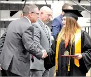  ??  ?? Baylie Slone is congratula­ted by school superinten­dent Keith Martin. Board president Jeff Neil passed out diplomas.