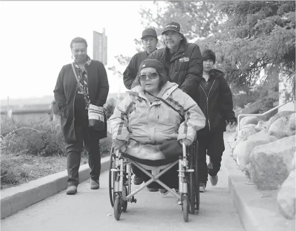  ?? THE CANADIAN PRESS ?? Marlene Bird, centre, is pushed along by friends and family members, who attended the sentencing hearing of Leslie Black in Prince Albert on Friday.