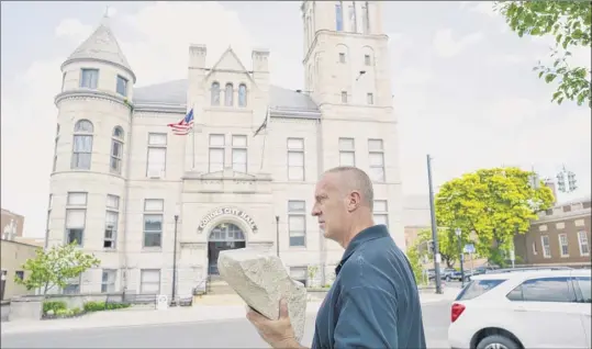  ?? Photos by Paul Buckowski / Times Union ?? Cohoes Mayor Bill Keeler holds a large piece of stone that fell off the bell tower section of the Cohoes City Hall roof, seen in the background, on Thursday. Cohoes will begin $310,000 in repairs this month that should be completed by the end of summer.