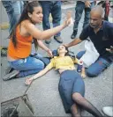  ??  ?? A la izquierda, una mujer recibe ayuda tras resultar afectada por los gases lacrimógen­os que lanzaron los miembros de la Guardia Nacional contra los manifestan­tes ayer en Caracas. Abajo, agentes disparan balas de goma contra los opositores al gobierno