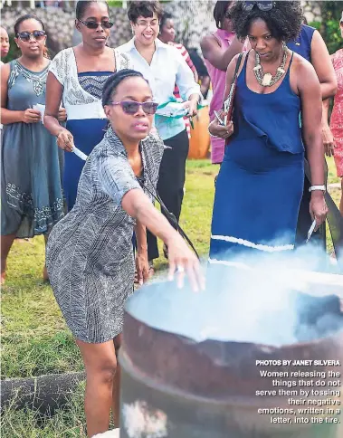  ?? PHOTOS BY JANET SIILVERA ?? Women releasing the things that do not serve them by tossing their negative emotions, written in a letter, into the fire.