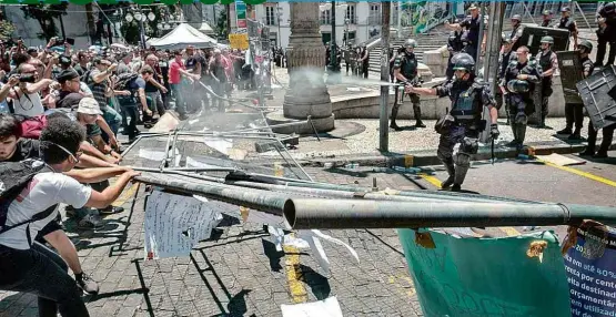  ??  ?? Servidores públicos quebram grades metálicas instaladas para proteger o prédio da Assembleia Legislativ­a do Rio e entram em confronto com policiais