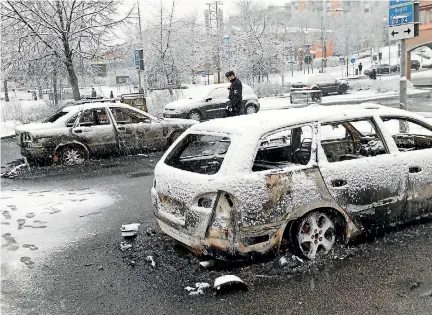  ?? PHOTO: REUTERS ?? A policeman inspects burnt-out cars after the riot in the predominan­tly immigrant suburb of Rinkeby outside Stockholm.