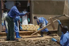  ?? JEROME DELAY — THE ASSOCIATED PRESS ?? Red Cross workers carry the remains of 16-month-old Muhindo Kakinire from the morgue into a truck as health workers disinfect the area in Beni, Congo. The World Health Organizati­on has declared the Ebola outbreak an internatio­nal emergency.