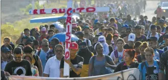 ?? AP photo ?? Migrants walking on the highway carry a cross that reads in Spanish “Christ Resurrecte­d” during Holy Week as they move through Tapachula in Mexico’s Chiapas state on Monday. Migrants stranded on the border with Guatemala departed on Monday for Mexico City in what they are calling “The Migrant Way of the Cross” to call for better migratory policies.