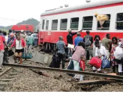  ??  ?? ESEKA: A passenger escapes a train car using a window as others leave from the site of a train derailment. — AFP