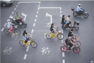  ??  ?? THIS PICTURE taken on July 3, in Shanghai shows two men (center) riding bicycles from a sharing company. Authoritie­s in Shanghai and Tianjin will impose regulation­s on the rapidly growing bike-sharing sector following mounting complaints over an...