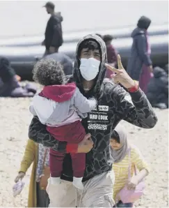  ?? ?? 0 People thought to be migrants make their way up a beach