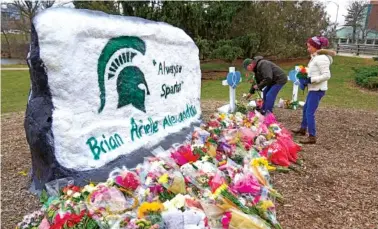  ?? AP PHOTO/PAUL SANCYA ?? Mourners leave flowers Wednesday at The Rock on the grounds of Michigan State University in East Lansing, Mich.