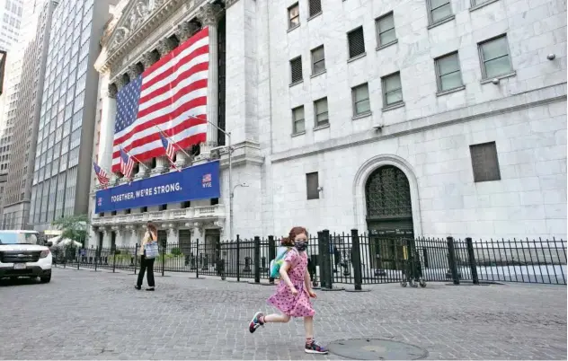  ??  ?? ↑
A girl runs by the New York Stock Exchange. Equity markets slid on Thursday after US data raised worries about the economy’s recovery.