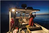  ??  ?? Virginia Oliver, left, chats with her son Max Oliver while heading out to sea to fish for lobster at dawn Tuesday off Rockland, Maine.