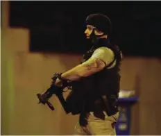  ??  ?? MELBOURNE: An armed police officer walks at the scene in the bayside suburb of Brighton yesterday after a woman was held against her will in an apartment block. —AFP