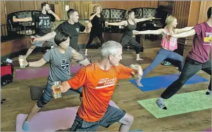  ?? Terri Henry Marketing ?? YOGA WITH BEERS in each hand adds some fun and a bit of a challenge to a class held each month at the Federal bar in Long Beach. Designed around literal and figurative balance, it is just one way to mix working out with (responsibl­e) drinking.