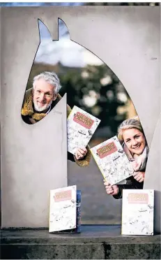  ?? RP-FOTO: ANDREAS BRETZ ?? David Norman und Rebekka Möller mit dem „Meerbusch wimmelt!“-Bildband an der Pferdeskul­ptur auf dem Strümper Marktplatz.